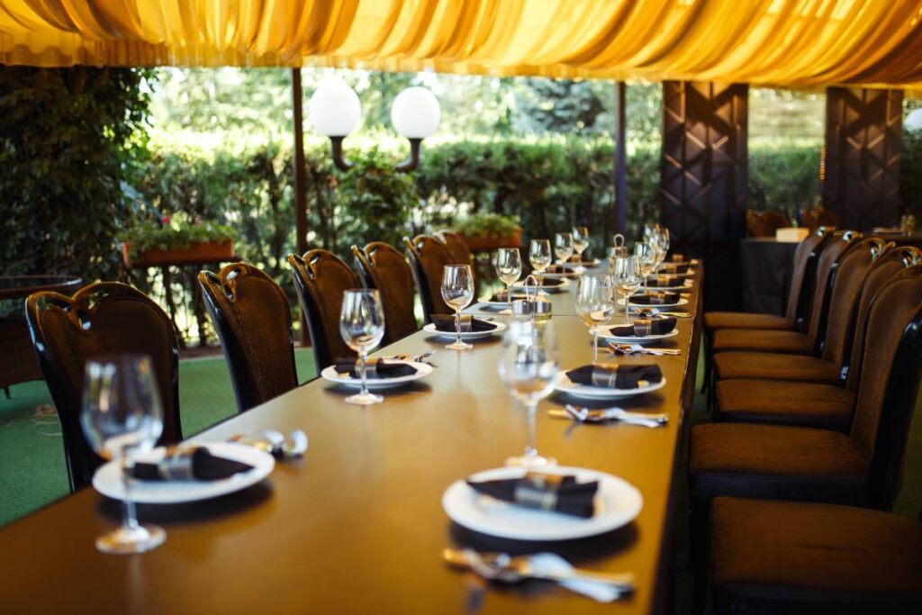 Sparkling glassware stands on long table prepared for wedding dinner.