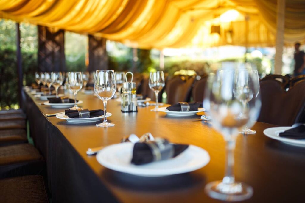 Sparkling glassware stands on long table prepared for wedding dinner.