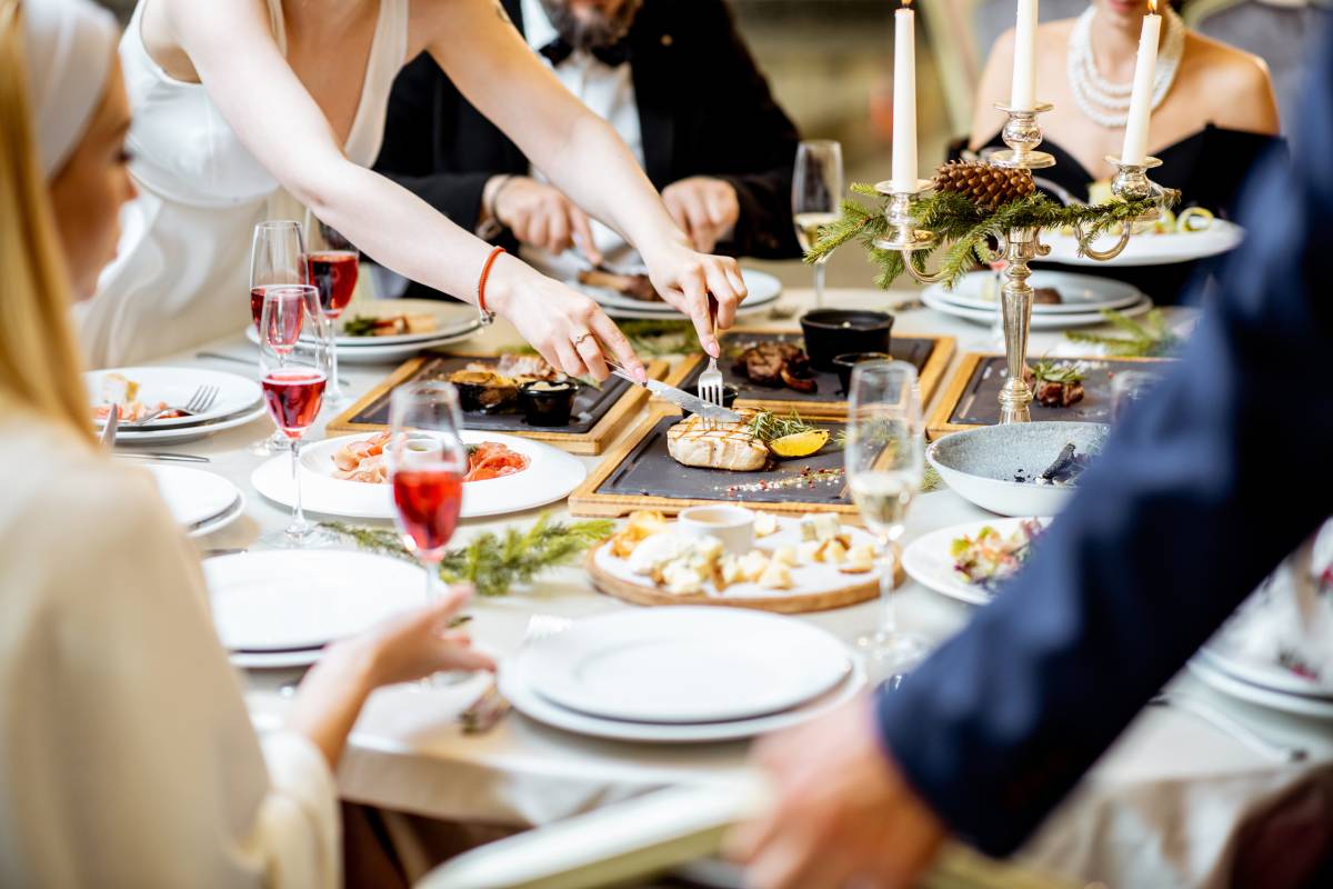 People having a festive dinner at a well-served table with tasty dishes during New Year Eve at the luxury restaurant, close-up view with no face