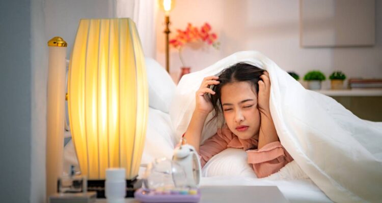 Asian young woman on the bed in the bedroom trying to wake up and prepare for work