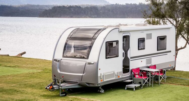 RV caravan camping at the caravan park on a peaceful lake with mountains on the horizon. Camping vacation family travel concept (RV caravan camping at the caravan park on a peaceful lake with mountains on the horizon. Camping vacation family travel co