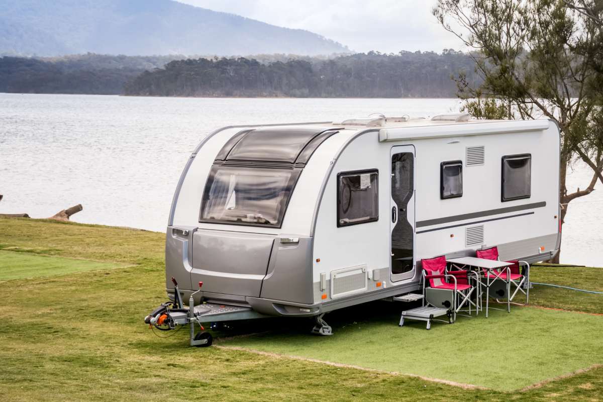 RV caravan camping at the caravan park on a peaceful lake with mountains on the horizon. Camping vacation family travel concept (RV caravan camping at the caravan park on a peaceful lake with mountains on the horizon. Camping vacation family travel co